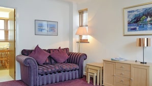 A living room with a sofa, a lamp, a small table, a cabinet, and a painting on the wall.