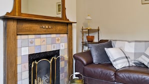A living room with a fireplace, a leather sofa, and a side table with a lamp. - 3 bedroom accommodation in Windermere (Windermere)