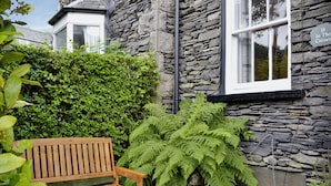 A stone building with a wooden bench and ferns in the yard. - 3 bedroom accommodation in Windermere (Windermere)