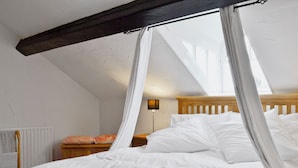 A bedroom with a wooden headboard, white bedding, a canopy bed, a nightstand with a lamp, and a radiator. - 3 bedroom accommodation in Windermere (Windermere)