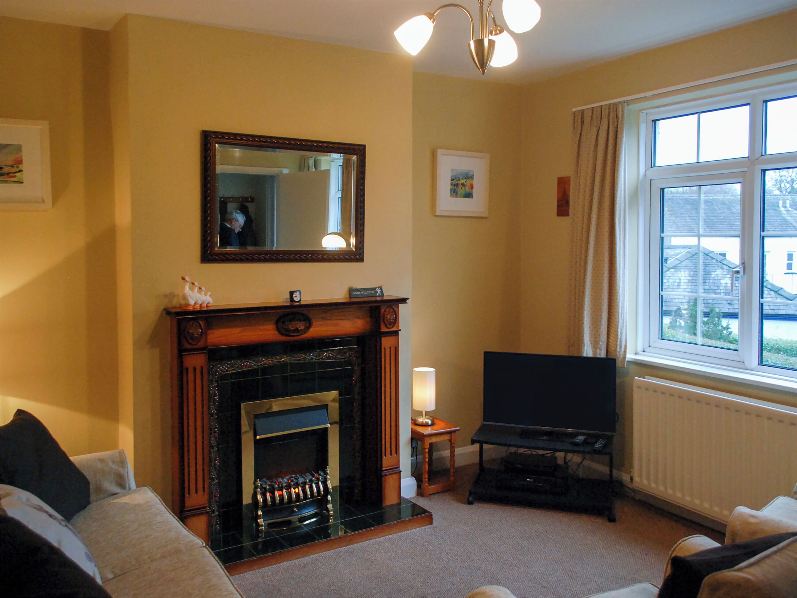 A living room with a fireplace, a television, and a window with a view of buildings.