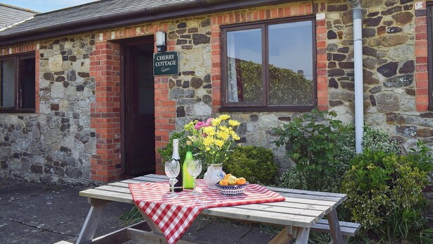 Ett litet stenhus med en skylt där det står ”Cherry Cottage”.