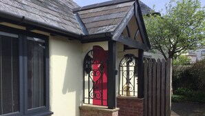 A house with a red door, a brick base, and a black metal gate.