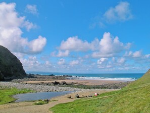 Eine Küstenlandschaft mit Strand, felsigem Ufer und einem kleinen Gewässer.