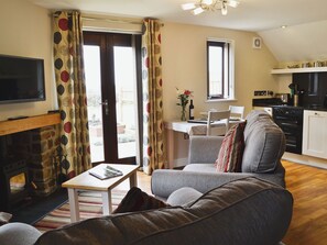 Ein Wohnzimmer mit Kamin, einer Couch, einem Fernseher und einem Essbereich mit Tisch und Stühlen.