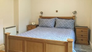 A wooden bed with a patterned bedspread, two bedside tables, and a radiator.