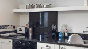 A kitchen with a black countertop, white cabinets, a toaster, a sink, and various kitchen utensils.