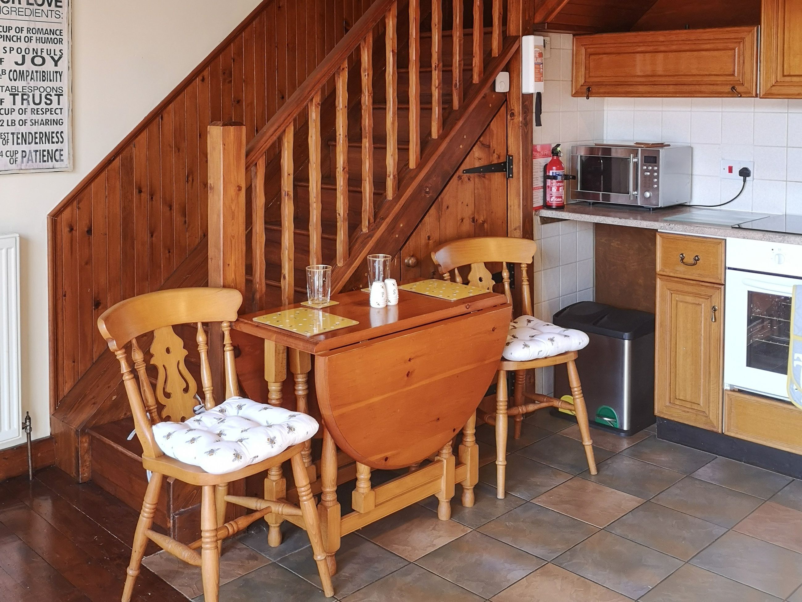A wooden staircase leading to a kitchen with a dining table and chairs.
