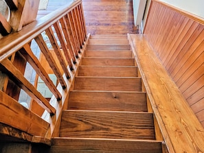 A wooden staircase with a handrail on both sides, leading to an upper floor.