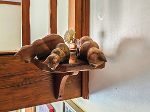 A wooden shelf with a decorative item resembling a dog, a glass vase with flowers, and a small bottle. - 1 bedroom accommodation in Freethorpe (Freethorpe)