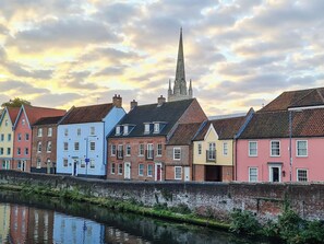 A row of colorful buildings along a canal with a church spire in the background.