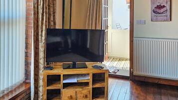 A wooden entertainment unit with a flat-screen TV, remote controls, and a small drawer.