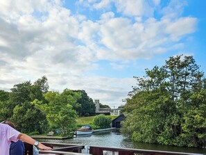 A river with a boat docked at a pier, surrounded by lush greenery and a historic building in the background. - 1 bedroom accommodation in Freethorpe (Freethorpe)
