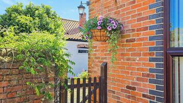A brick building with a wooden gate, a hanging flower basket, and a clear blue sky.