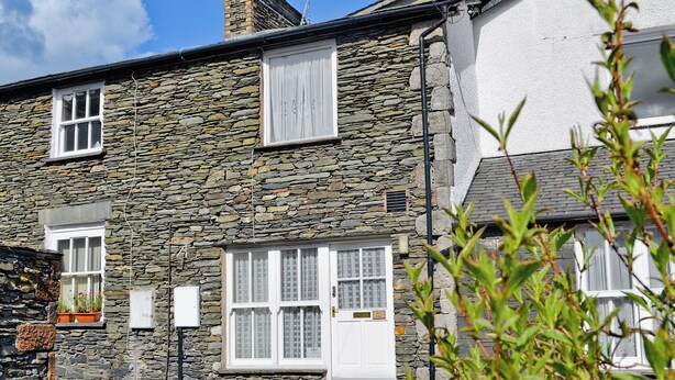 A stone house with two windows and a door, surrounded by greenery. - 1 bedroom accommodation in Windermere (Windermere)