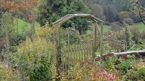 Ein hölzerner Kletterbogen mit Vogelhäusern in einem Garten.