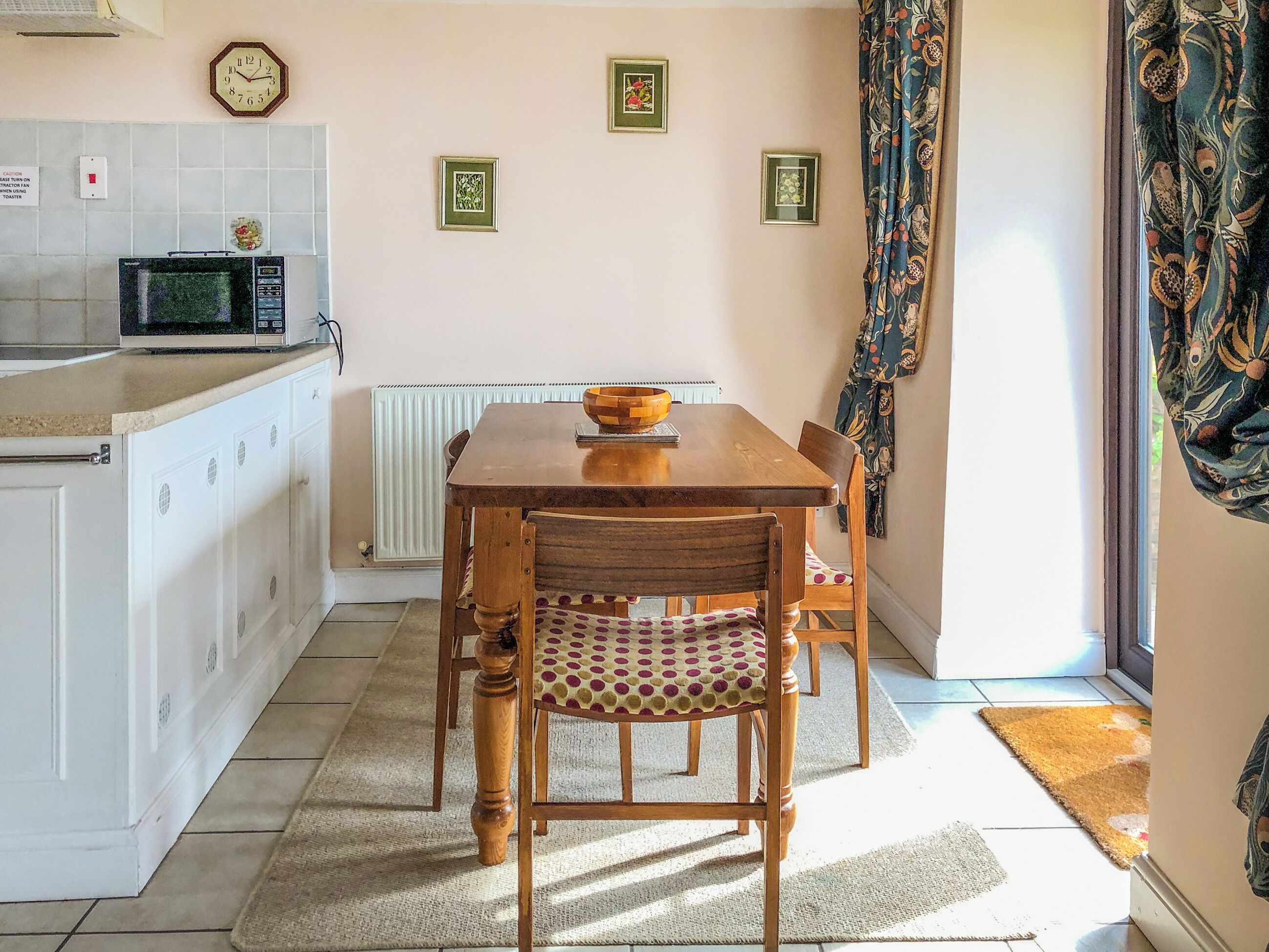 Une cuisine avec une table en bois, des chaises, un four à micro-ondes et des tableaux encadrés accrochés au mur.