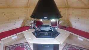 Ein gemütliches Blockhaus-Interieur mit Holzofen, rotem Sofa und gemusterten Kissen.