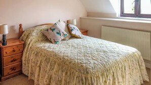 Ein Schlafzimmer mit einem Bett, zwei Nachttischen, einer Lampe und einem Fenster mit Blick.