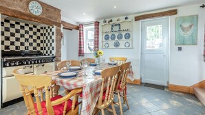 Un comedor con mantel a cuadros, sillas de madera y una estufa antigua.