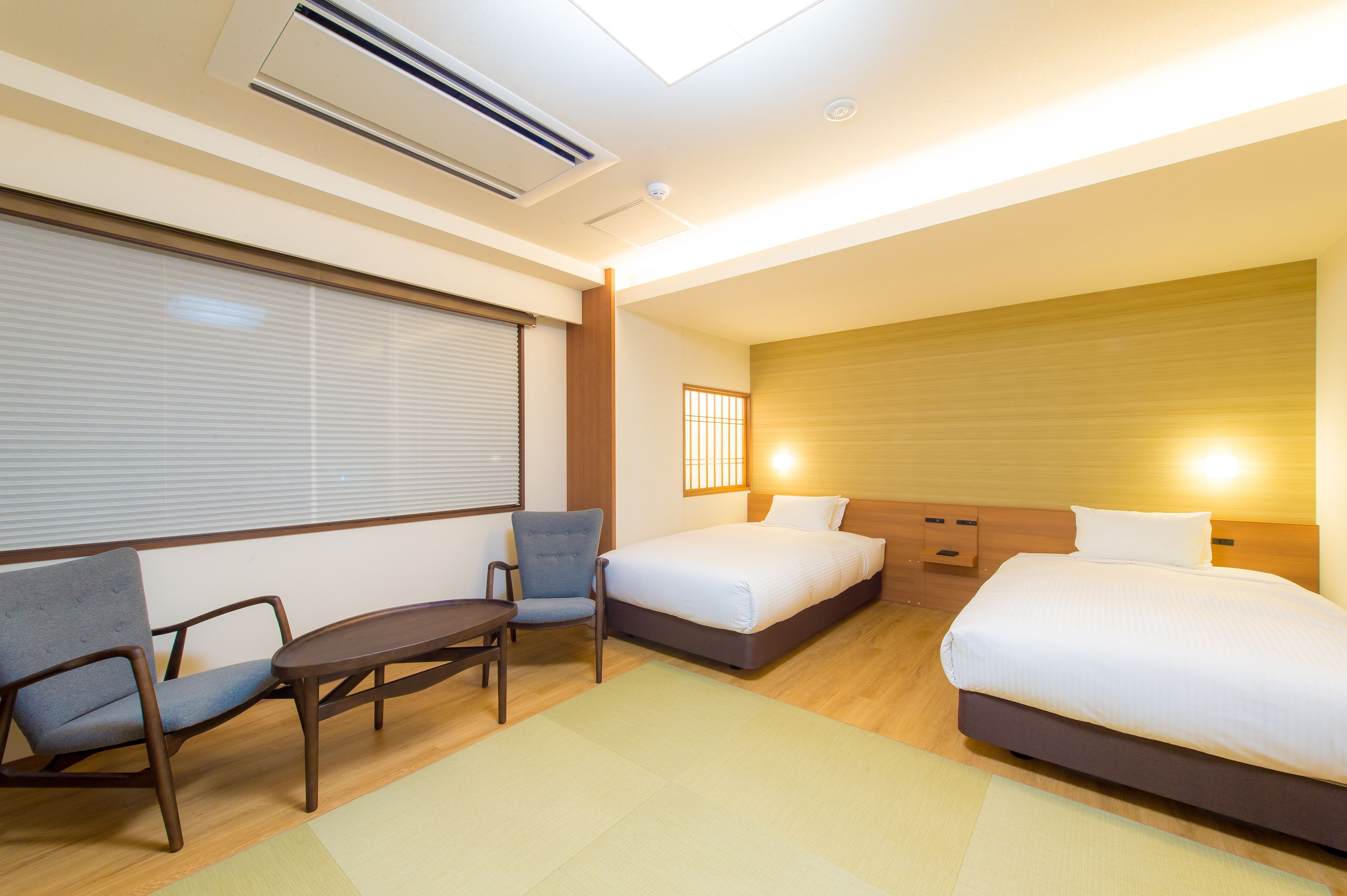A hotel room with two beds, a desk, and a chair.