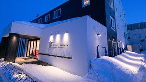 A hotel entrance with a snow-covered path leading to the door, illuminated by exterior lights. - Hotel Munin Furano (Furano)