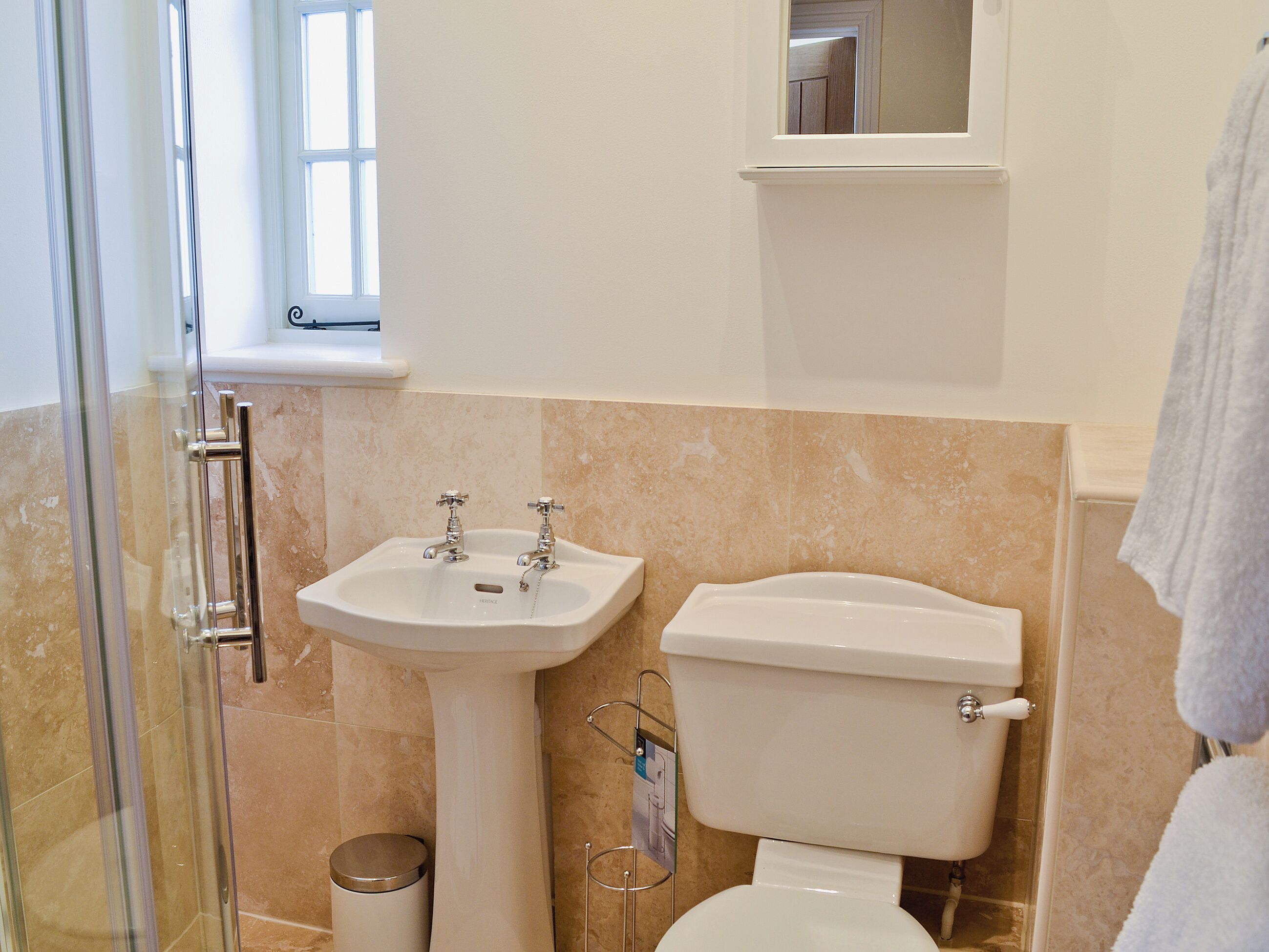 Un baño con lavamanos, inodoro y cabina de ducha de vidrio.
