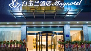 A hotel entrance with a revolving door, a sign above the door, and a number sign indicating room 139. - Magnotel Hotel –South Railway Station, Huizhou (Huizhou)