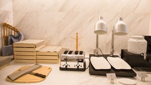 A kitchen area with a marble countertop, two white lamps, a toaster, a cutting board, a knife, and a wooden chair. - Magnotel Hotel –South Railway Station, Huizhou (Huizhou)