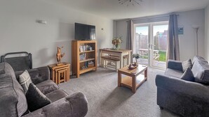 A living room with two sofas, a coffee table, a bookshelf, and a television.