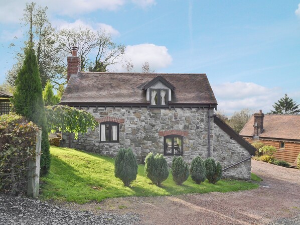 A stone house with a sloped roof, a chimney, and a small porch.
