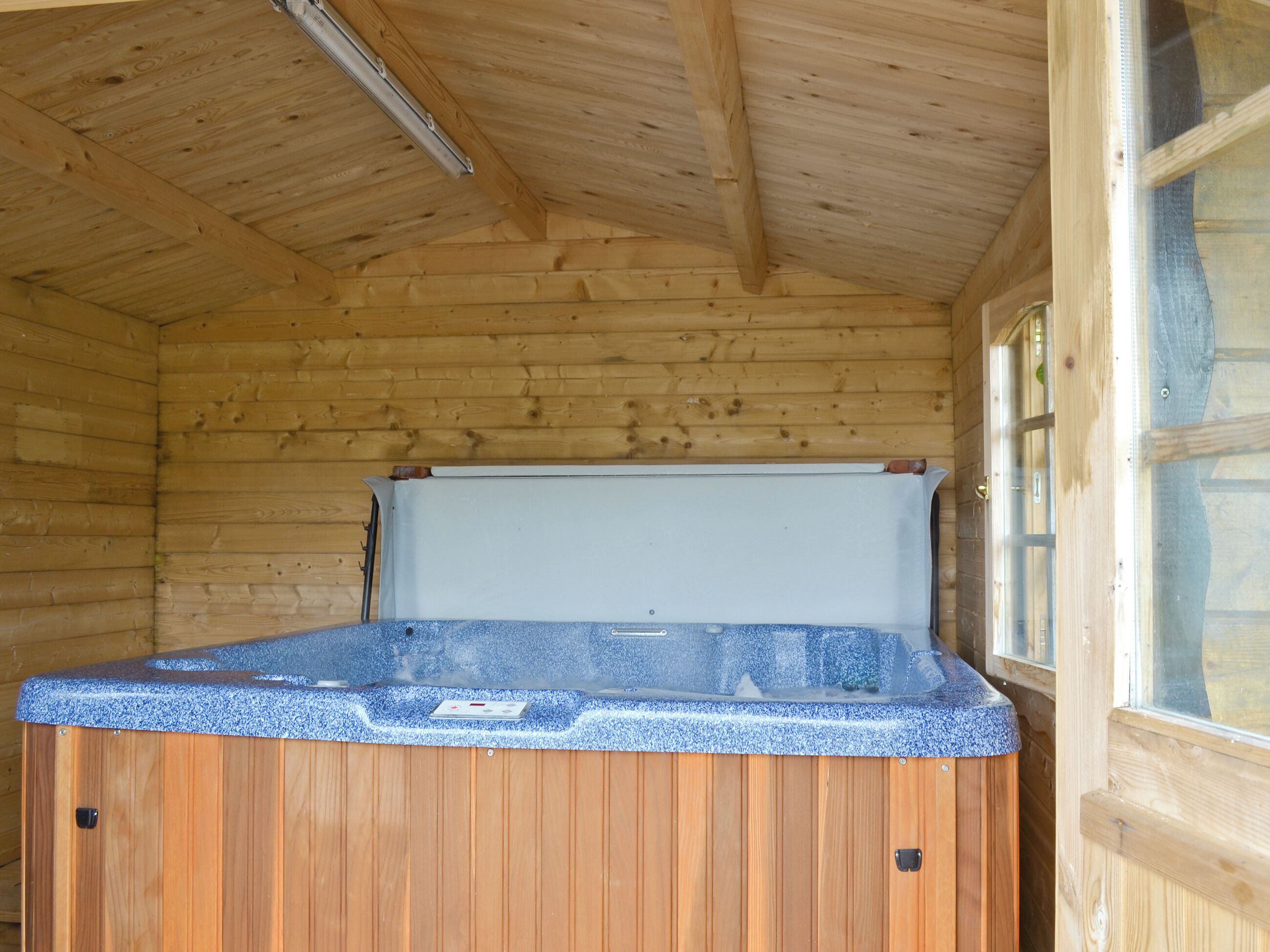 Een houten chalet met een hottub in het midden.