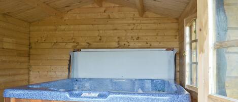Een houten chalet met een hottub in het midden.