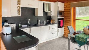 A modern kitchen with white cabinets, a black countertop, and a built-in microwave.