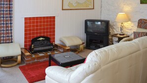 Een woonkamer met een open haard, een televisie, een bank en een kaart aan de muur.
