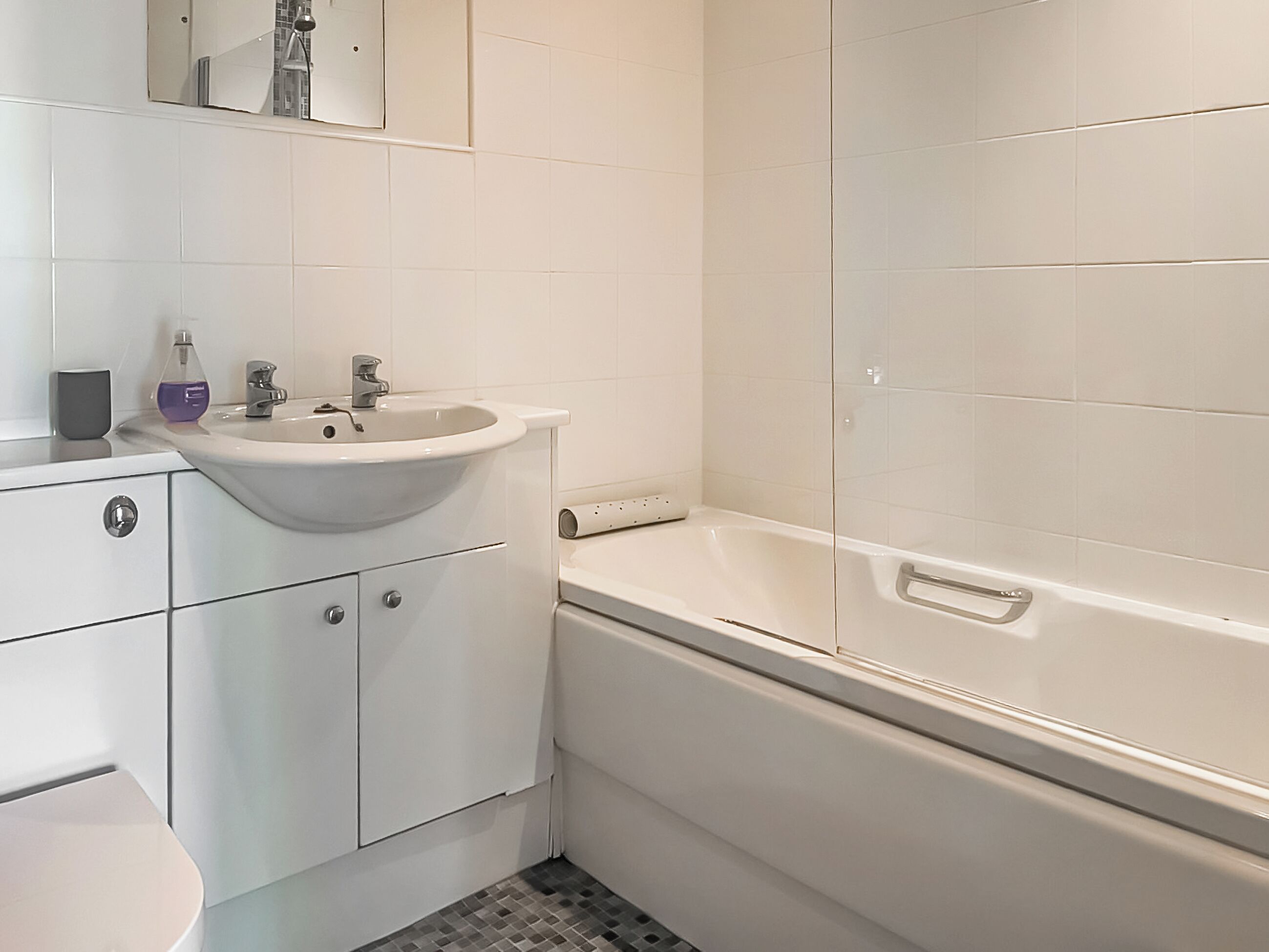 Een badkamer met wastafel, spiegel, toilet en bad.