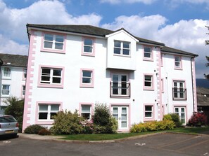 A multi-story residential building with pink-framed windows and a flat roof.