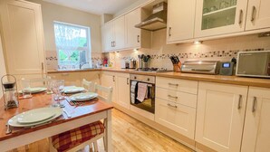 Een moderne keuken met witte kastjes, een houten eettafel en een raam dat voor natuurlijk licht zorgt.