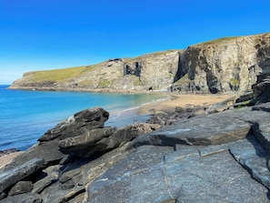 Eine Küstenlandschaft mit felsigen Klippen, einem Sandstrand und klarem, blauem Wasser.
