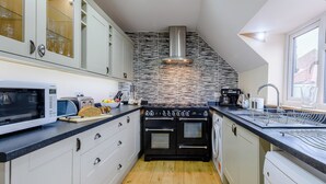 A modern kitchen with white cabinets, a black stove, a microwave, and a Bosch dishwasher. - 4 bedroom accommodation in Wells-next-the-Sea (Wells-next-the-Sea)