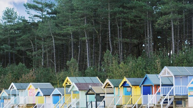 A row of beach huts with stairs leading up to them, set against a backdrop of trees. - 4 bedroom accommodation in Wells-next-the-Sea (Wells-next-the-Sea)