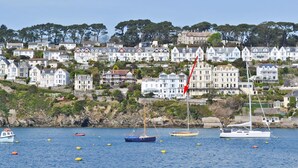 A coastal town with houses on a hillside, boats on the water, and a clear sky.