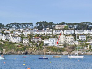 A coastal town with houses on a hillside, boats on the water, and a clear sky.