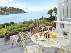 A table set for breakfast with a view of the sea, surrounded by chairs and potted plants. - 2 bedroom accommodation in Fowey (Fowey)