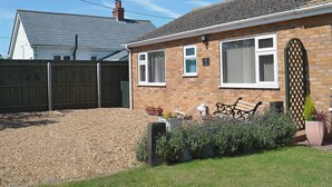 A two-story house with a brick exterior, a tiled roof, and a fenced backyard. - 2 bedroom accommodation in Heacham (Heacham)