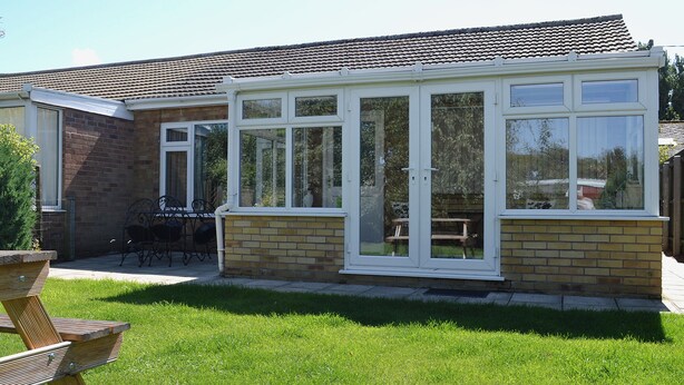 A house with a conservatory, brick walls, and a tiled roof. - 2 bedroom accommodation in Heacham (Heacham)