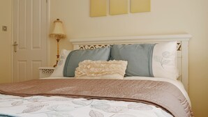A bedroom with a bed, a nightstand, a lamp, and a door. - 2 bedroom accommodation in Heacham (Heacham)