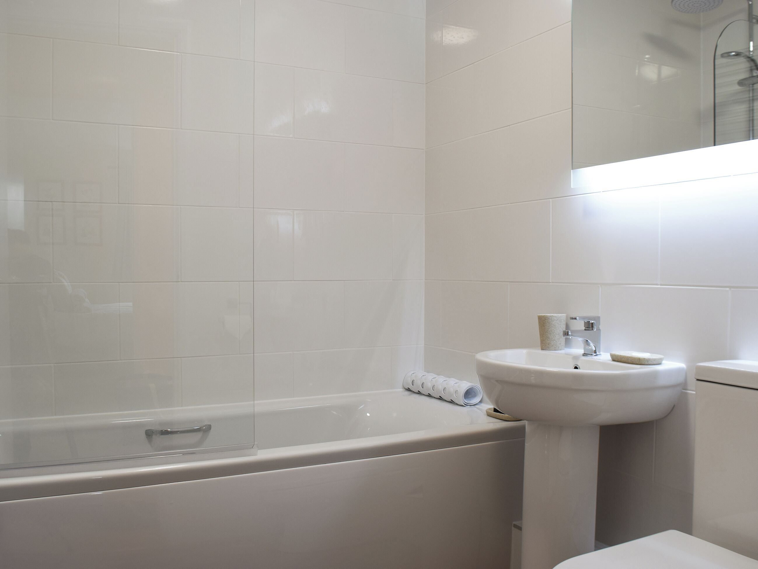 Un baño con bañera, lavabo y espejo.
