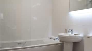 Un baño con bañera, lavabo y espejo.