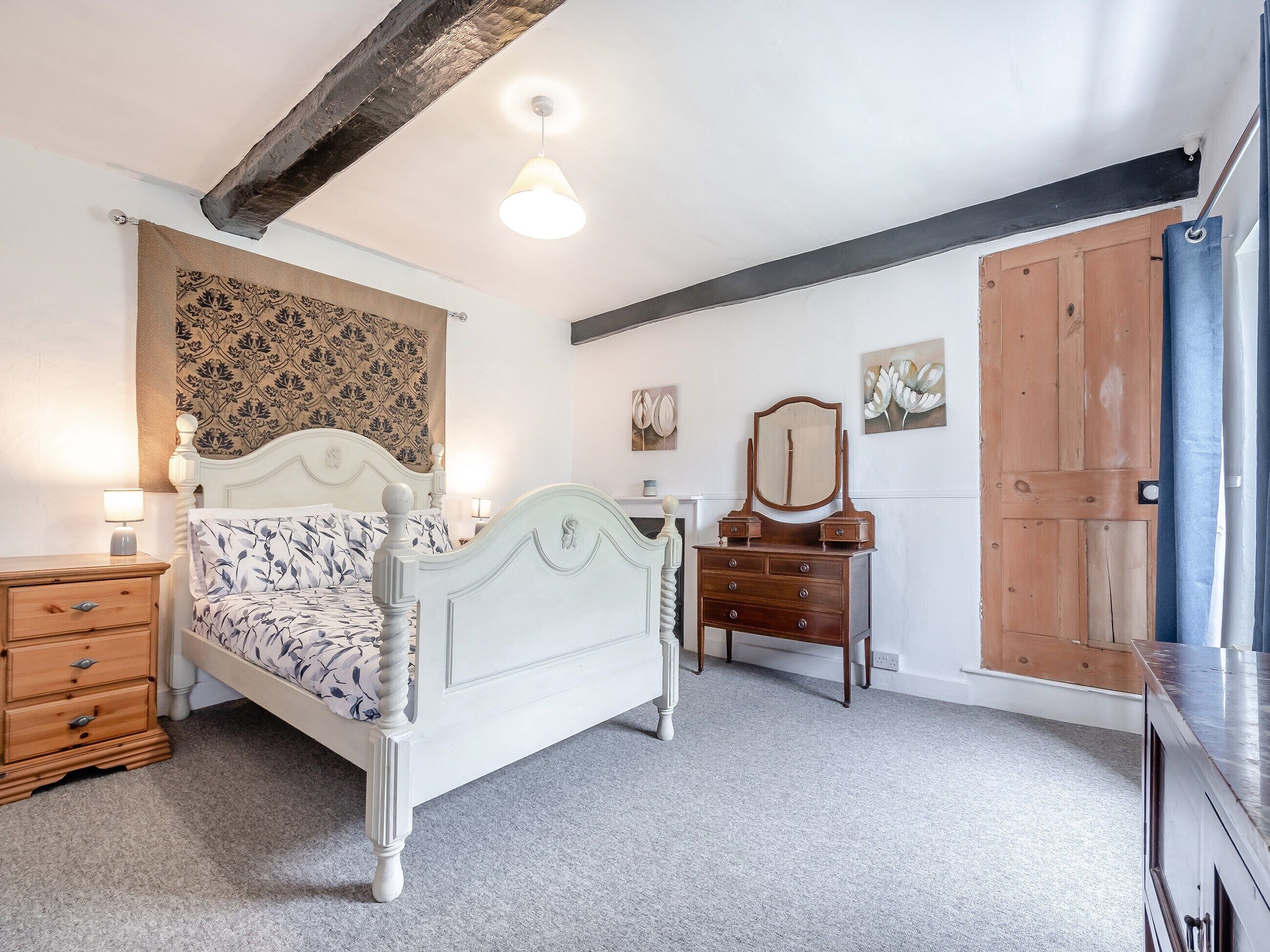A bedroom with a bed, dresser, and a wooden door.